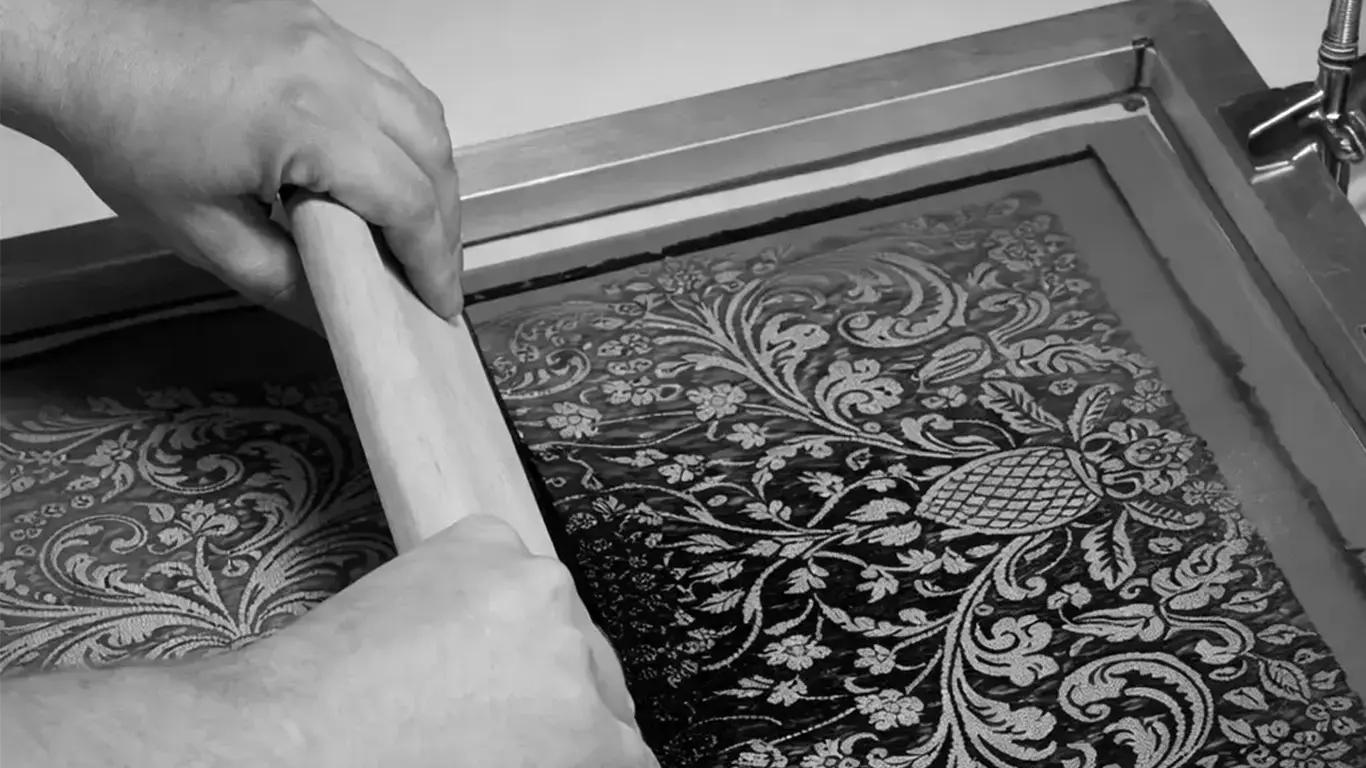 Textile savoir-faire immersion in Lyon with artisan hands printing a decorative fabric pattern